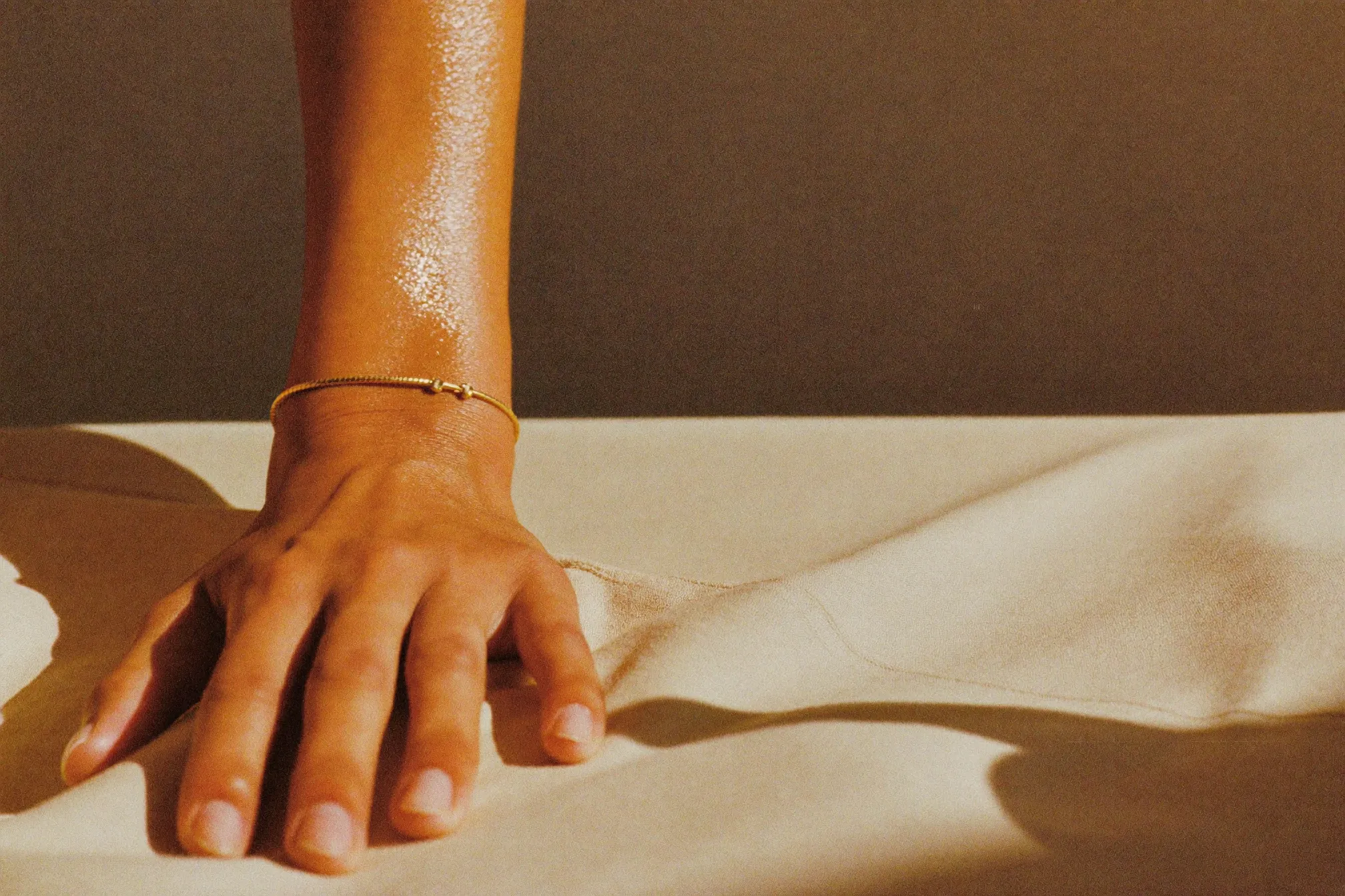 A bronzed forearm resting on linen